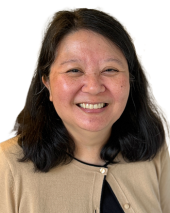 Professional headshot of a woman with long dark hair, wearing a tan cardigan over a black top, smiling at the camera.