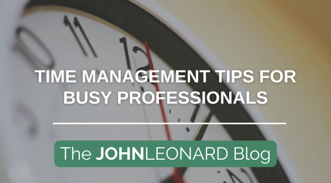 Close-up of a clock face in the background with bold white text overlay that reads 'Time Management Tips for Busy Professionals.' Below, a green banner says 'The JOHNLEONARD Blog.'