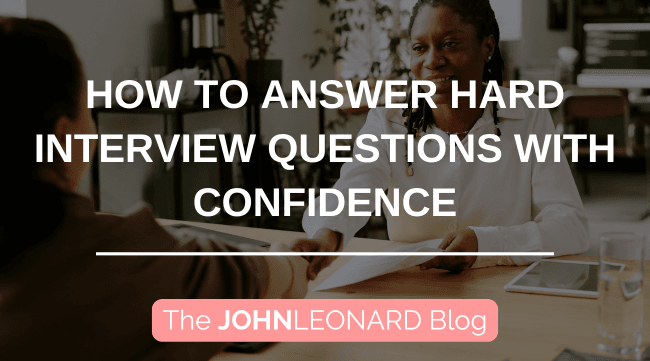 Blog graphic showing a professional job interview setting, with two people seated across a desk shaking hands while reviewing documents. Large overlay text reads “How to Answer Hard Interview Questions with Confidence” with JOHNLEONARD branding at the bottom.